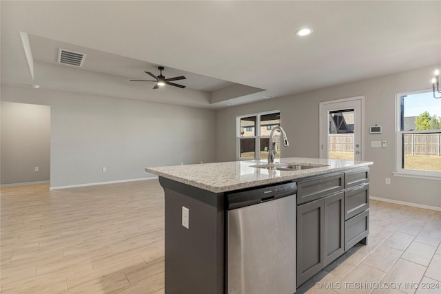 kitchen with stainless steel dishwasher, ceiling fan with notable chandelier, sink, light hardwood / wood-style floors, and an island with sink