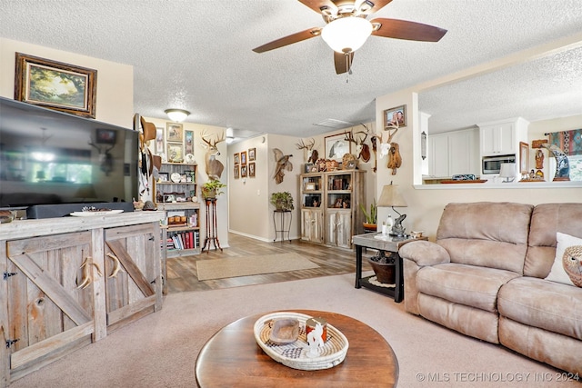 living room featuring a textured ceiling, light hardwood / wood-style flooring, and ceiling fan