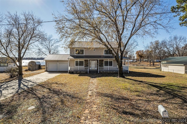 view of front of home featuring a garage, covered porch, and a front yard