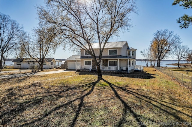 view of front of home with a front lawn, a porch, a water view, and a garage