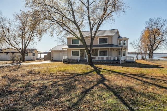 view of front of property featuring a garage, covered porch, a water view, and a front lawn