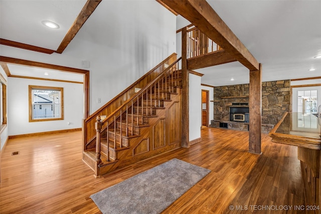 staircase featuring hardwood / wood-style flooring, a wood stove, and ornamental molding