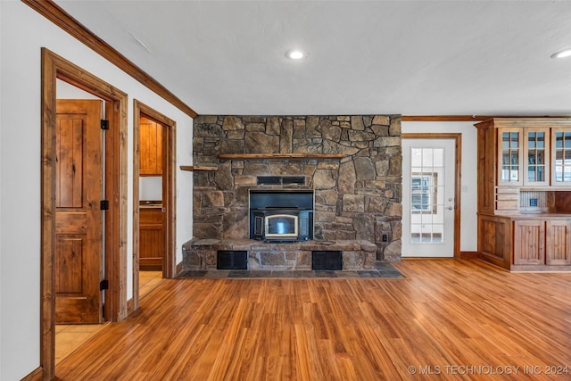 unfurnished living room featuring light hardwood / wood-style floors, a wood stove, and crown molding