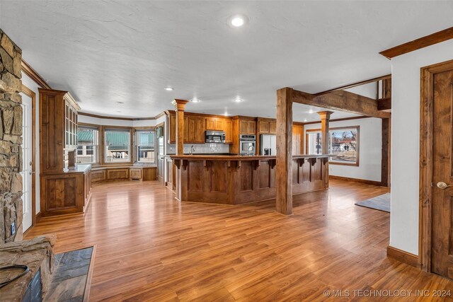 kitchen featuring light hardwood / wood-style floors, kitchen peninsula, ornamental molding, and appliances with stainless steel finishes