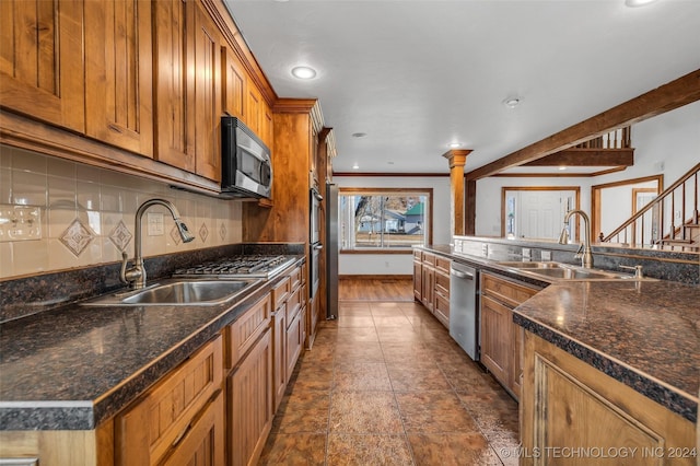 kitchen featuring decorative backsplash, appliances with stainless steel finishes, a kitchen island, and sink