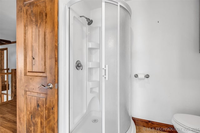 bathroom featuring hardwood / wood-style floors, an enclosed shower, and toilet