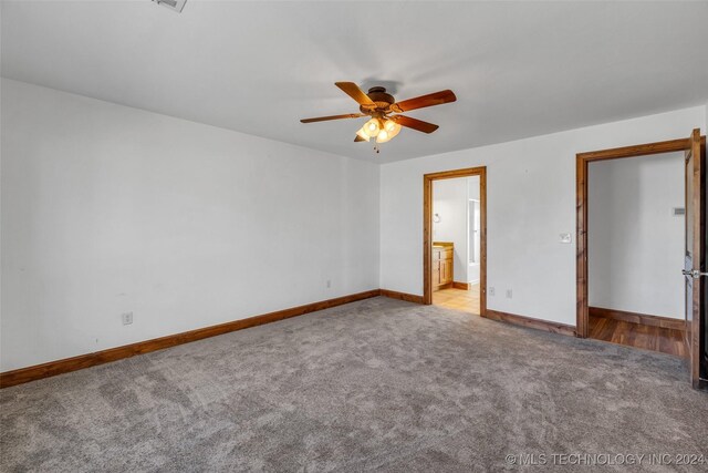 interior space with ensuite bath, ceiling fan, and light colored carpet