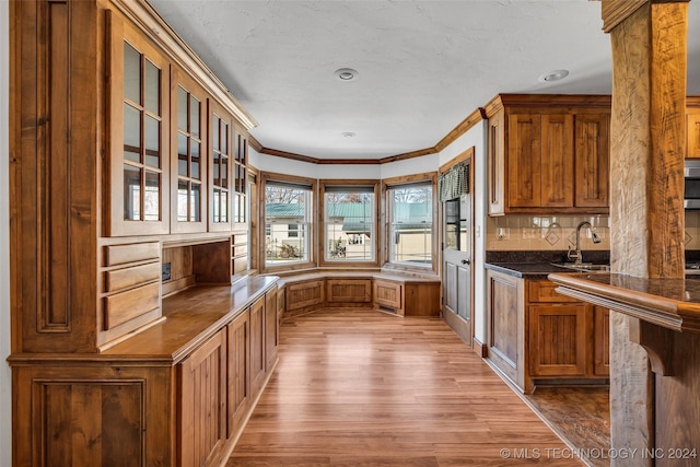 kitchen with decorative backsplash, light hardwood / wood-style floors, sink, and crown molding