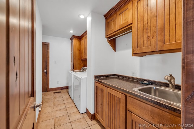 laundry area featuring washer and clothes dryer, sink, light tile patterned floors, and cabinets