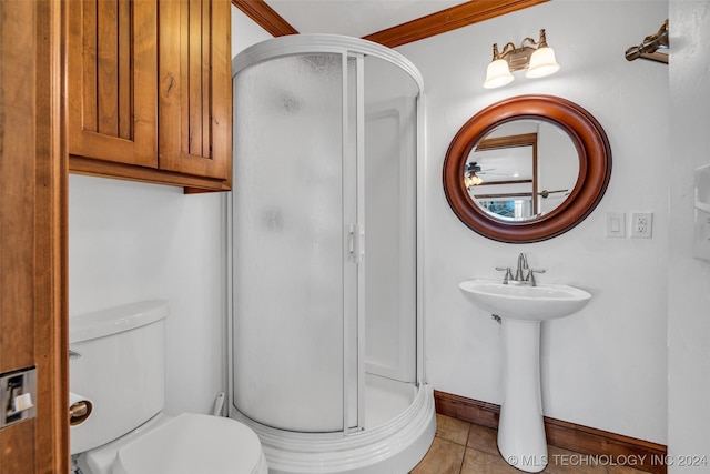 bathroom featuring tile patterned floors, ornamental molding, a shower with door, sink, and toilet