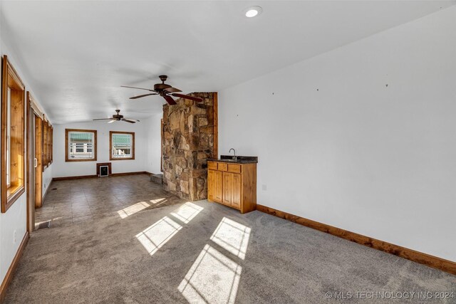 unfurnished living room with ceiling fan, sink, dark carpet, and vaulted ceiling