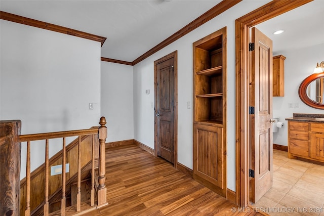 corridor with light hardwood / wood-style floors and ornamental molding