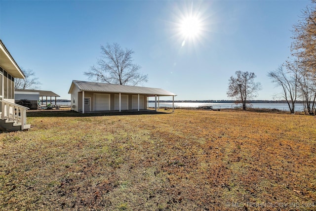 view of yard with a carport, a water view, and an outdoor structure