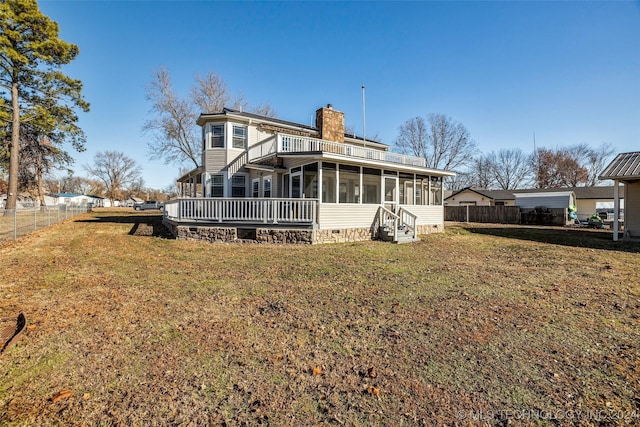 back of property featuring a yard, a balcony, and a sunroom