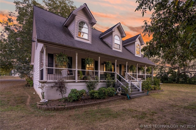 new england style home featuring a lawn and covered porch