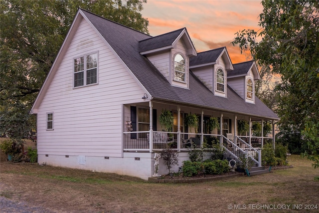 cape cod-style house with a porch and a yard