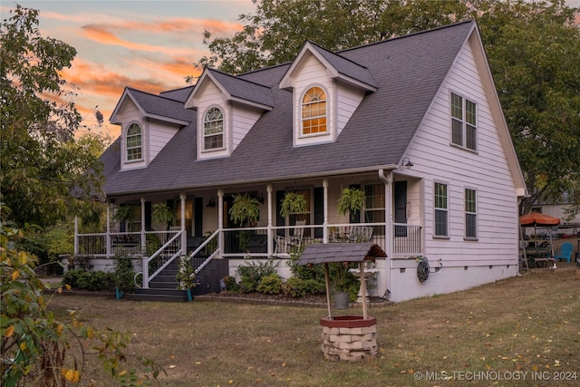 cape cod home featuring a lawn and a porch