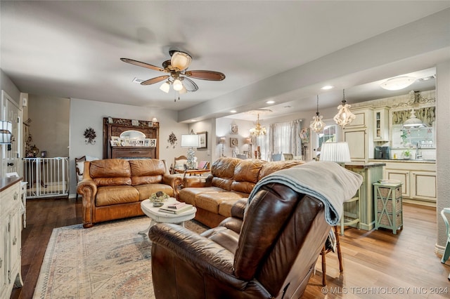 living room featuring sink, ceiling fan with notable chandelier, and hardwood / wood-style flooring