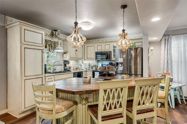 kitchen featuring wood counters, cream cabinets, a textured ceiling, wood-type flooring, and stainless steel appliances