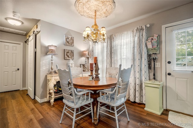 dining area with hardwood / wood-style floors, a barn door, and an inviting chandelier