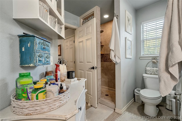 bathroom featuring toilet, tile patterned flooring, and tiled shower