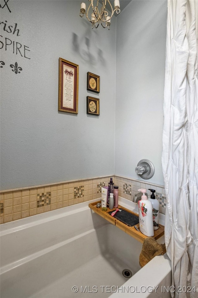 bathroom featuring a notable chandelier, a bath, and tasteful backsplash