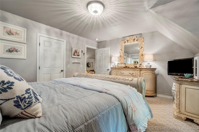 carpeted bedroom with a textured ceiling and vaulted ceiling