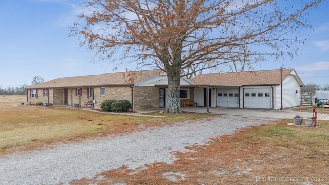 single story home with driveway, stone siding, an attached garage, and a front yard