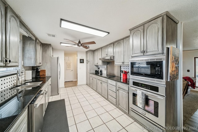 kitchen featuring dark countertops, black appliances, under cabinet range hood, and a sink