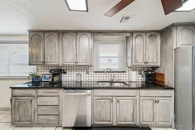 kitchen featuring stainless steel appliances, a sink, visible vents, a ceiling fan, and dark stone counters