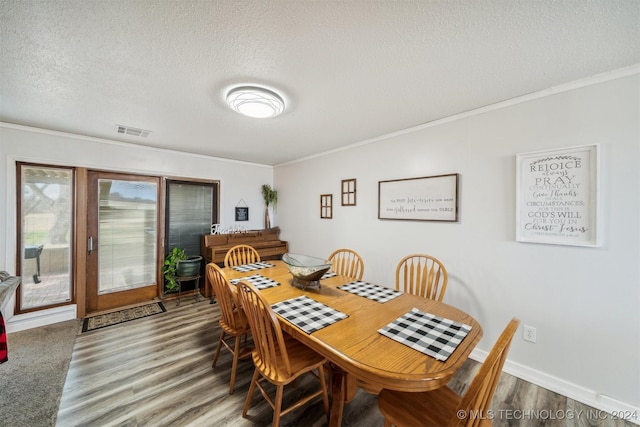 dining room with ornamental molding, visible vents, a textured ceiling, and wood finished floors