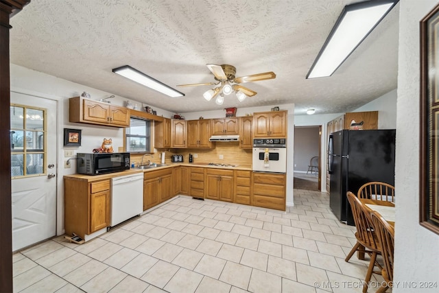 kitchen featuring brown cabinets, under cabinet range hood, light countertops, black appliances, and a sink