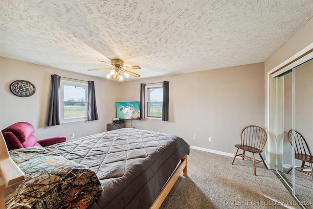 bedroom with carpet, a closet, a ceiling fan, a textured ceiling, and baseboards