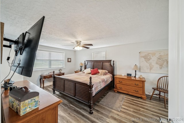 bedroom with a textured ceiling, ceiling fan, and light wood finished floors