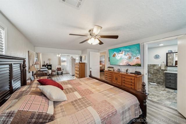 bedroom with visible vents, a ceiling fan, connected bathroom, a textured ceiling, and wood finished floors