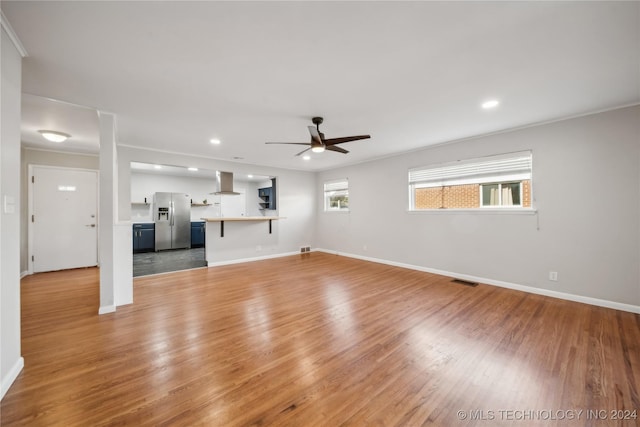 unfurnished living room featuring wood-type flooring, ceiling fan, and crown molding