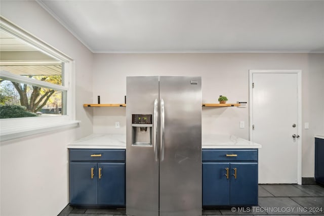 kitchen with light stone counters, dark tile patterned floors, stainless steel refrigerator with ice dispenser, blue cabinets, and ornamental molding