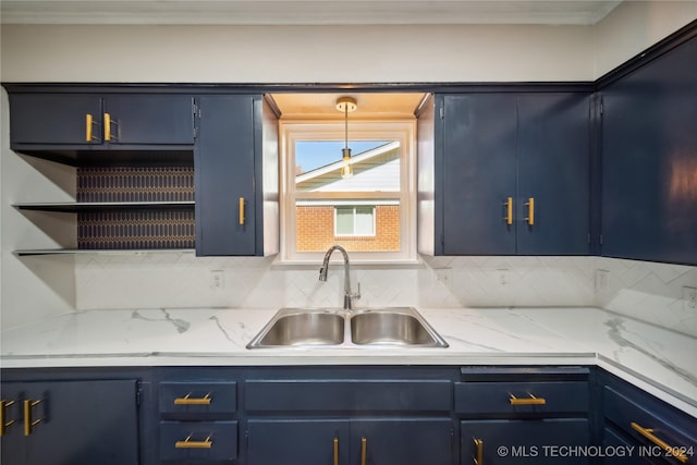 kitchen featuring blue cabinetry, backsplash, hanging light fixtures, and sink