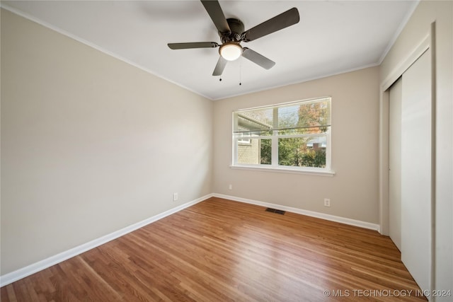 unfurnished bedroom with hardwood / wood-style flooring, ceiling fan, crown molding, and a closet