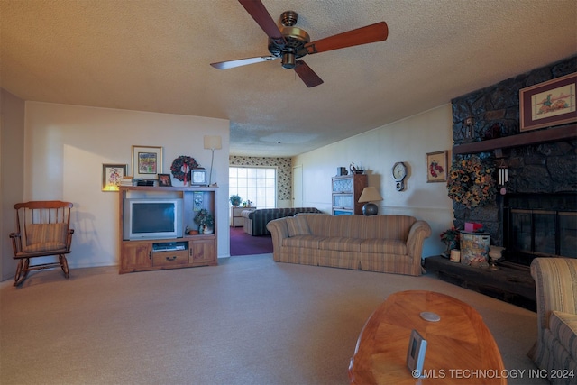 living room featuring a stone fireplace, ceiling fan, and a textured ceiling