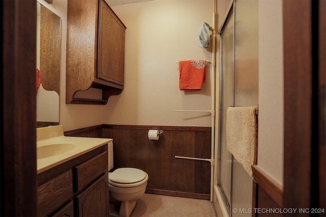 bathroom featuring vanity, wood walls, an enclosed shower, and toilet