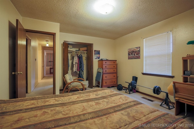 bedroom featuring a textured ceiling, light colored carpet, and a closet