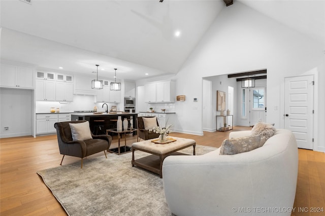 living room featuring light hardwood / wood-style flooring, high vaulted ceiling, and sink