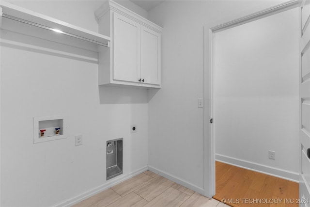 clothes washing area featuring hookup for an electric dryer, cabinets, hookup for a washing machine, and light hardwood / wood-style flooring