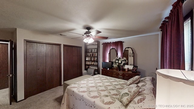 carpeted bedroom featuring multiple closets and ceiling fan