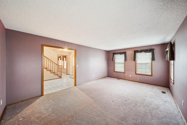 spare room with light colored carpet and a textured ceiling