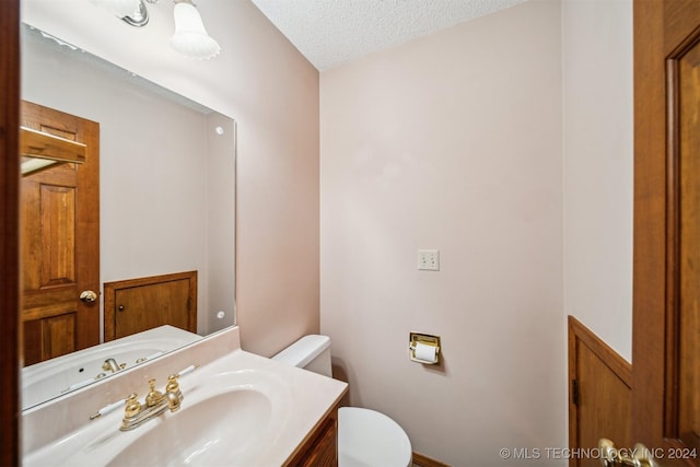 bathroom with vanity, a textured ceiling, and toilet