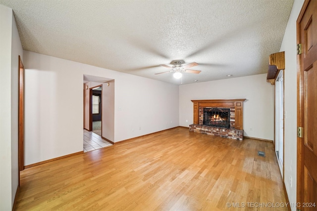 unfurnished living room featuring a fireplace, a textured ceiling, and light hardwood / wood-style floors