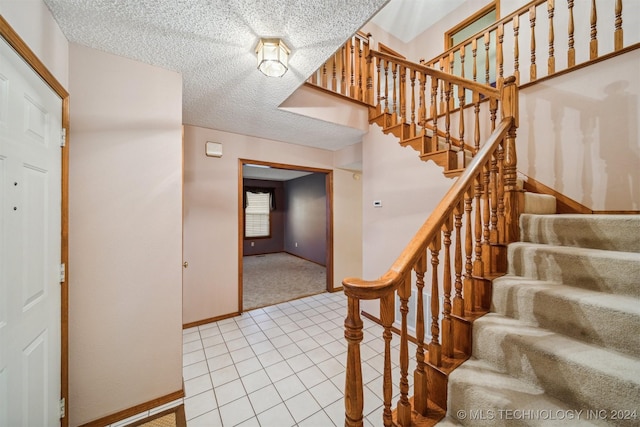 stairway with carpet floors and a textured ceiling