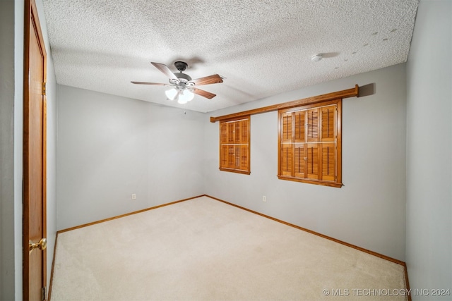 carpeted spare room featuring ceiling fan and a textured ceiling